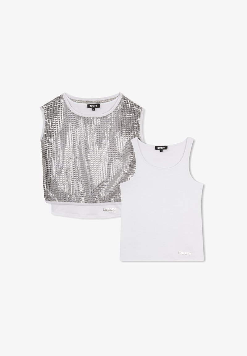 Deux hauts sans manches DKNY : un débardeur blanc et un crop-top sans manches à sequins argentés. Les deux portent le logo de la marque près de l'ourlet.
