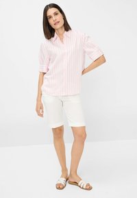 Light pink and white striped shirt with a button-up front, paired with white knee-length shorts and light strap sandals.
