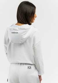 Felpa bianca con cappuccio, dal taglio rilassato e con polsini a costine, caratterizzata dal logo nero "ICE ICEBERG" sulla schiena. Realizzata in morbido tessuto misto cotone.