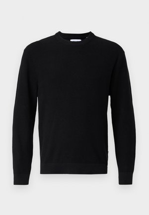 Sort langærmet sweater med rund hals, ribstrikket tekstur og tætsiddende manchetter, vist på en ensartet lysegrå baggrund.