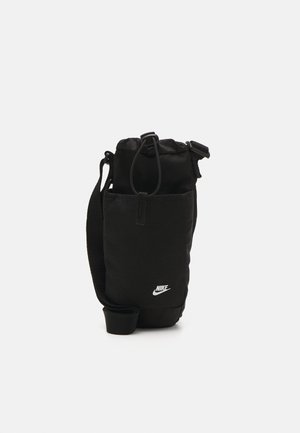 Schwarze Nike Schultertasche mit Fronttasche, verstellbarem Gurt, Kordelzugverschluss und weißem Logo auf der Vorderseite vor neutralem Hintergrund.