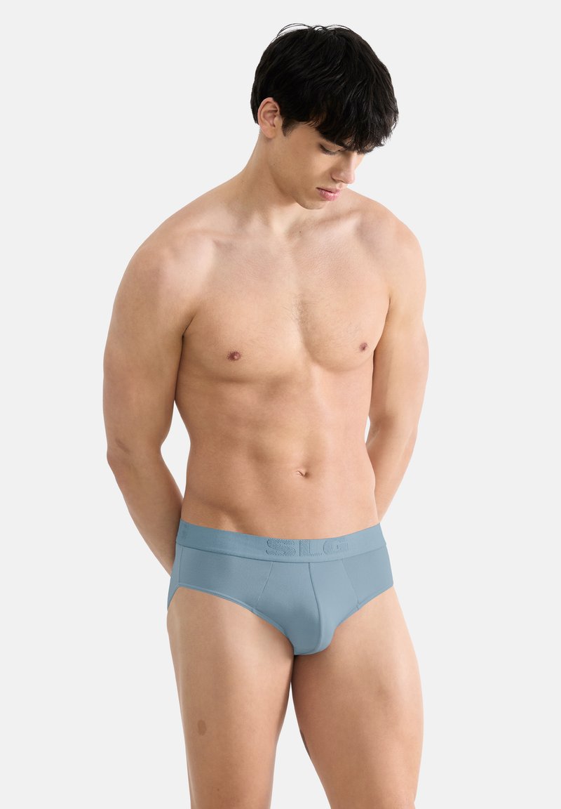 Slip en coton bleu avec une texture lisse. Comprend une large ceinture avec un logo embossé. Conçu pour un ajustement près du corps, offrant une couverture modérée.