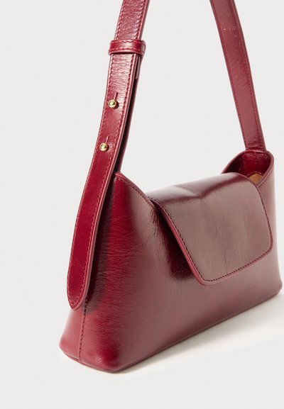 Saco de ombro em couro vermelho com uma textura suave, design angular, fecho de aba e uma alça ajustável slim com detalhes em ouro.