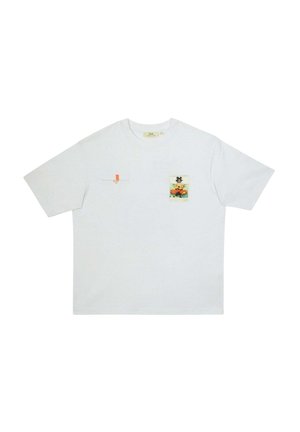 T-shirt blanc à manches courtes avec un petit patch imprimé d'un personnage animé assis sur le côté gauche de la poitrine et un petit onglet orange sur le côté droit de la poitrine.