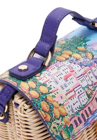 Borsa in paglia intrecciata con manico in pelle viola, con una patta colorata decorata con case e frutti agrumi.