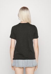 Schwarzes Baumwoll-T-Shirt mit kurzen Ärmeln, Rundhalsausschnitt und lockerem Schnitt, kombiniert mit einem hellen, plissierten Jeansrock.