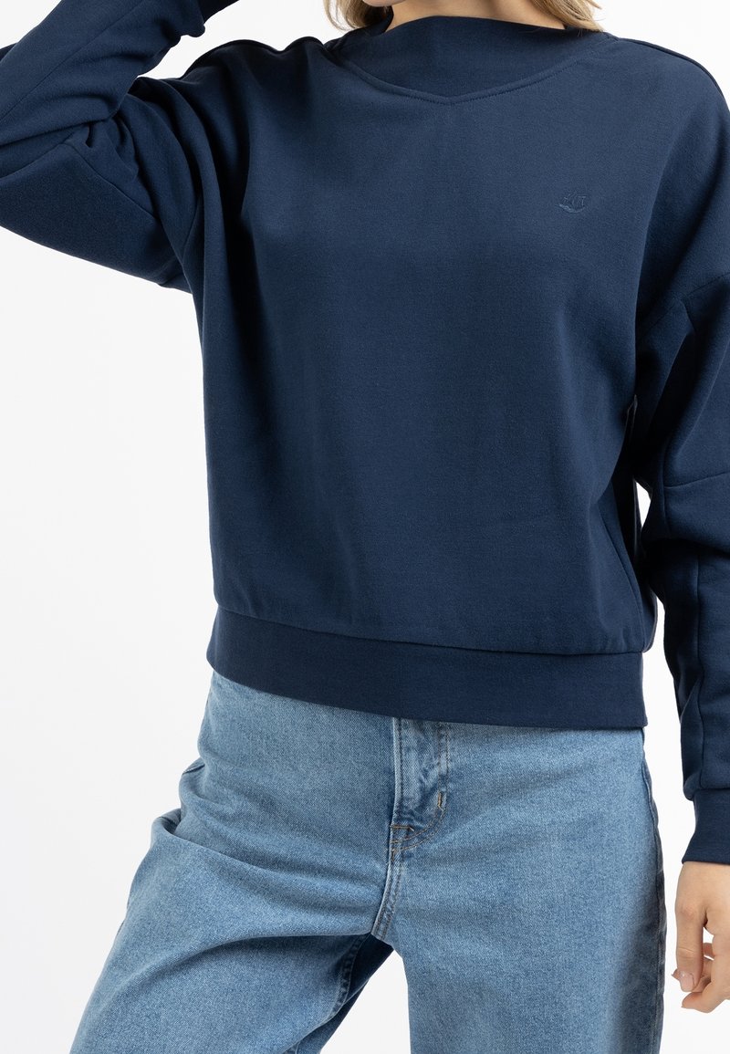 Sweat-shirt bleu marine avec col rond, manches longues et ourlet côtelé. Fabriqué dans un tissu doux, avec un petit logo sur la poitrine.