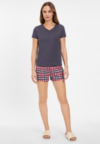 Camiseta gris de cuello en V combinada con pantalones cortos de cuadros rosas. Material de algodón suave, ajuste casual, los pantalones cortos presentan un patrón a cuadros con acentos en negro y azul.