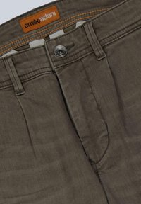 Olive green trousers made of soft cotton, featuring a zipper fly, button closure, and contrasting orange brand label at the waistband.