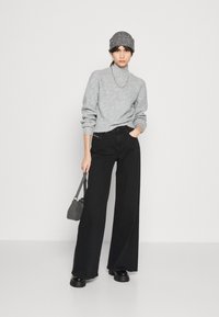 Suéter cinza de malha, jeans pretos de perna larga, botas chunky pretas, chapéu cinza texturizado e uma pequena bolsa cinza. Linhas simples e limpas em cores neutras.