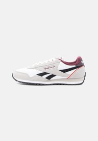 Bijela i siva Reebok tenisica s crnim logotipima, bordo unutarnjim postavom i crvenim akcentom na peti, prikazana sa strane.