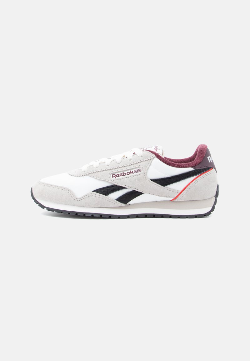 Bijela i siva Reebok tenisica s crnim logotipima, bordo unutarnjim postavom i crvenim akcentom na peti, prikazana sa strane.