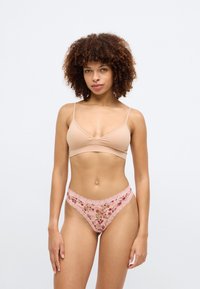 Μπέζ άνετο σουτιέν χωρίς ραφές με λεπτές τιράντες και ροζ δαντελένιο thong με λουλουδάτα σχέδια, που παρουσιάζει ένα ημιδιαφανές σχέδιο από πλέγμα.