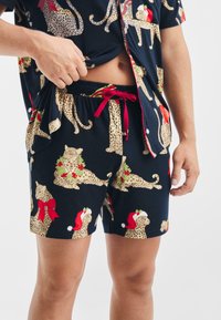 Granatowy zestaw piżamowy z wzorem w panterkę i świątecznymi akcentami, czerwone szorty ze sznurkiem, lekki materiał, krótkie rękawy.