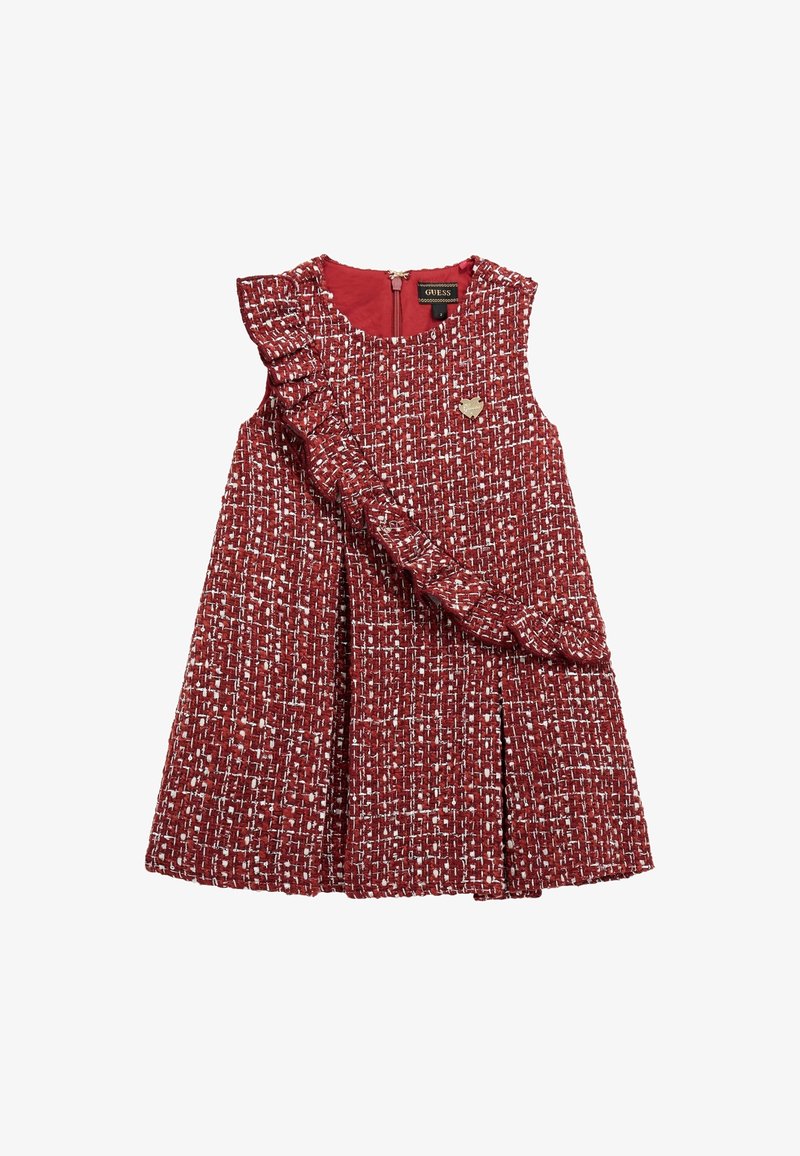 Robe sans manches en tweed rouge et blanc avec une ceinture à volants sur le devant, une jupe plissée et un petit emblème en forme de cœur doré sur la poitrine.