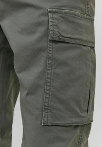 Cargo-Hosen aus dunkelgrünem Stoff. Merkmale sind seitliche Taschen, robuste Nähte und eine glatte Textur. Leicht und praktisches Design.