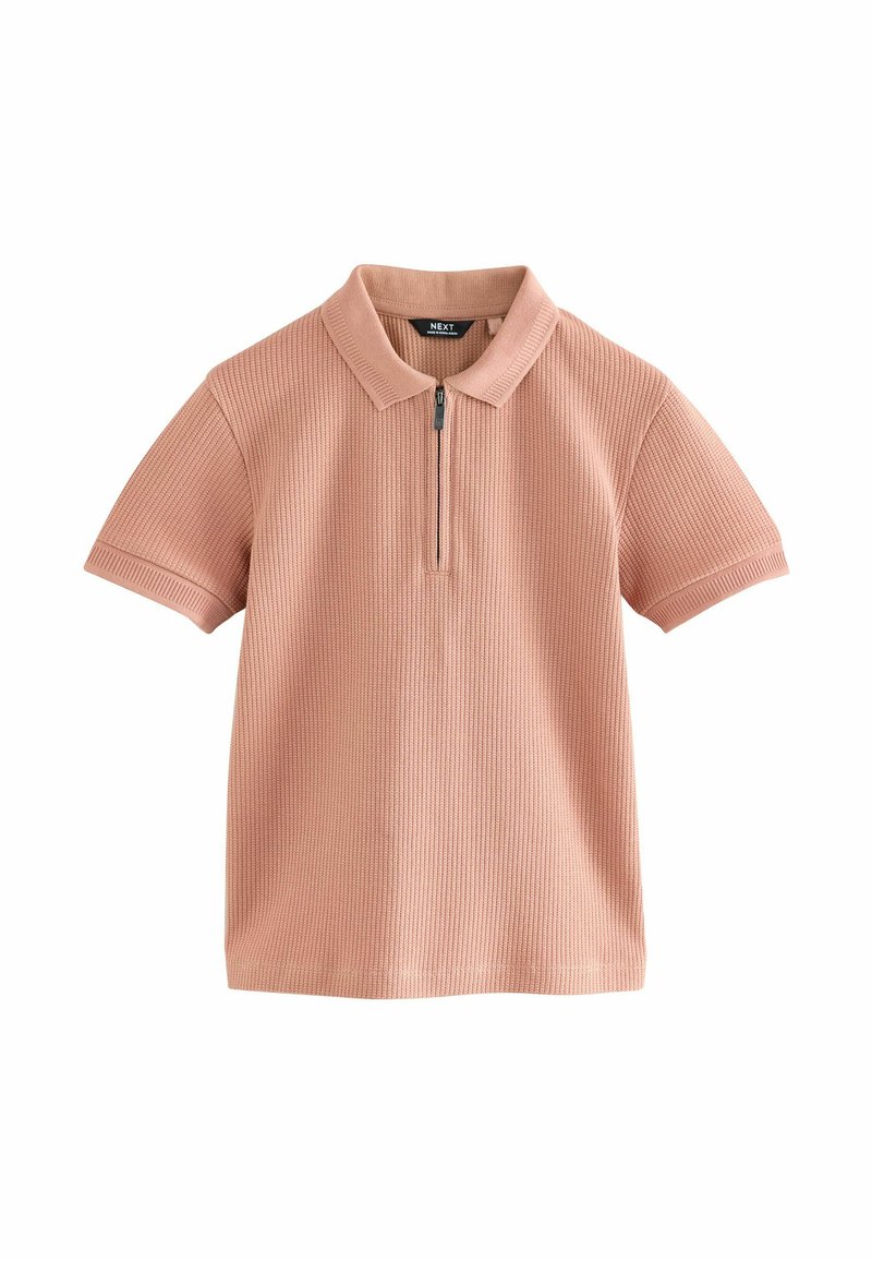 Polo à manches courtes en rose doux, texture côtelée, avec un col et une fermeture éclair à moitié à l'avant. Design minimaliste avec des lignes épurées.