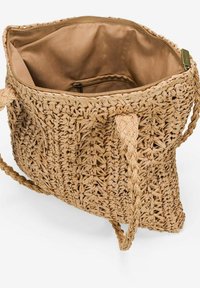 Bolso de tote de paja trenzada con asas trenzadas, parte superior abierta y un interior de tela marrón claro con un pequeño bolsillo con cremallera.