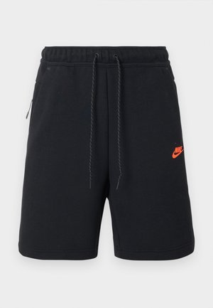 Črne Nike kratke hlače z elastičnim pasom, vrvico za zategovanje, stranskimi žepi in majhnim oranžnim Nike logotipom na levi stegni.