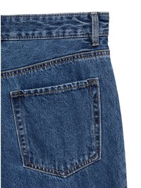 Zadnji pogled na denim kavbojke, z velikim žepom, kontrastnim šivanjem in svetlo modrim pranjem z teksturirano obdelavo.