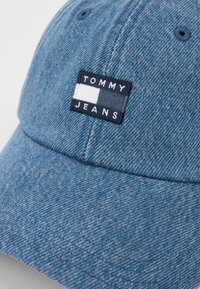 Μπλε τζιν καπέλο μπέιζμπολ με ραμμένο ορθογώνιο λογότυπο που λέει "TOMMY JEANS" και σχέδιο σε λευκό και σκούρο μπλε χρώμα.