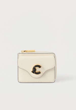 Cream leather cardholder with black logo accent and gold hardware. Features a zip closure and rounded flap design. Compact and functional.