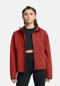 Giubbotto rosso con zip e cappuccio, realizzato in un tessuto liscio. Caratterizzato da dettagli neri sulle spalle e due tasche frontali. Abbinato a una maglietta corta nera.