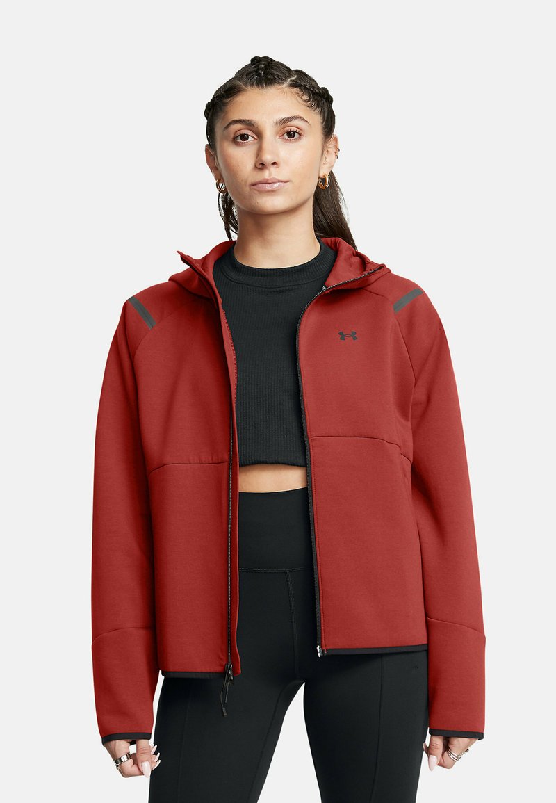 Giubbotto rosso con zip e cappuccio, realizzato in un tessuto liscio. Caratterizzato da dettagli neri sulle spalle e due tasche frontali. Abbinato a una maglietta corta nera.