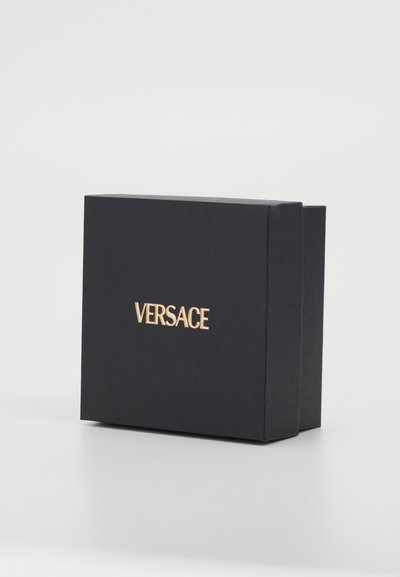 Κουτί δώρου Versace, μαύρο υλικό με υφή, ορθογώνιο σχήμα, διαθέτει χρυσό ανάγλυφο λογότυπο μπροστά, μίνιμαλ σχέδιο, χωρίς ορατά μοτίβα.