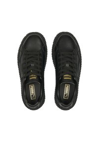 Černé kožené tenisky s kulatou špičkou, texturovanou podrážkou, plochými tkaničkami a zlatým logem značky na jazyku a boku. Hladký povrch.