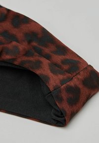 Látka s leopardím potiskem v odstínech hnědé a černé, s texturovaným designem, hladkým černým podšívkou a elastickým lemem.