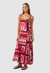Maxi jurk met een gedurfd rood en wit bloemen- en geometrisch patroon. Heeft spaghettibandjes met decoratieve accenten en een vloeiende zoom.