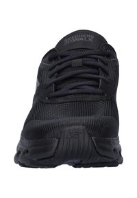Scarpa da ginnastica nera con tomaia in rete, chiusura con lacci e colletto imbottito. Presenta una suola testurizzata e il marchio Skechers sulla linguetta.