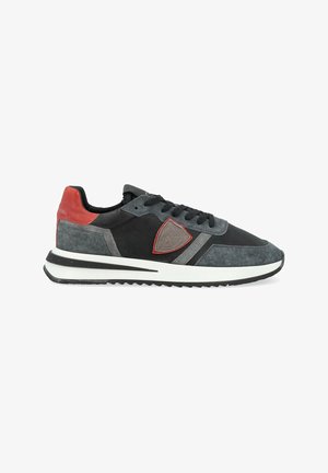 Sneaker da uomo con tomaia in suede nero e grigio, dettagli rossi, patch con logo e suola bianca. Presenta un tessuto testurizzato e un design snello.