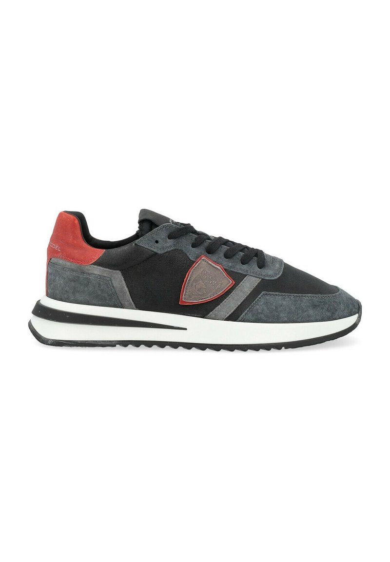 Sneaker da uomo con tomaia in suede nero e grigio, dettagli rossi, patch con logo e suola bianca. Presenta un tessuto testurizzato e un design snello.