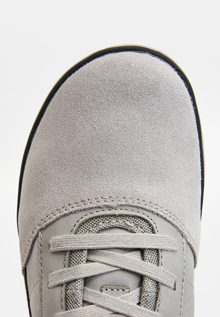 Punta di scarpa in suede grigio con finitura testurizzata, punta rotonda e lacci intrecciati. Presenta un collare imbottito e un bordo della suola nera a contrasto.