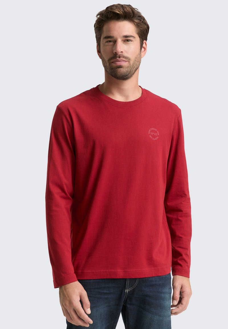 Rode longsleeve t-shirt van zachte katoen met een ronde hals. Heeft een subtiele logoafdruk in een lichtere tint op de borst.