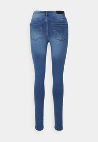 Jeans skinny de denim azul com uma cintura média, apresentando dois bolsos traseiros e uma textura suave. Sem desgastes visíveis ou adornos.