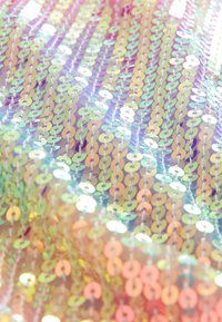 Rangées de sequins irisés sur un tissu transparent reflétant des couleurs pastel en motifs doux et ondulés.