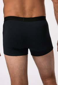 Černé bavlněné boxerky s hladkým povrchem, přiléhavým střihem a elastickým pasem s embosovaným logem.