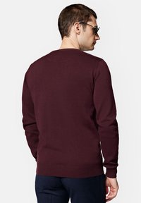 Bordowy sweter z okrągłym dekoltem, z prążkowanymi mankietami i dołem, wykonany z miękkiej dzianiny. Charakteryzuje się gładką fakturą, bez widocznych wzorów czy grafik.