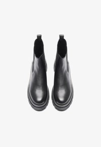 Botas Chelsea de cuero negro con paneles laterales elásticos y tira para el talón, con suela de goma gruesa y textura suave y brillante.