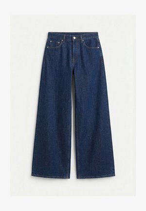 Σκούρο μπλε τζιν παντελόνι με φαρδιά μπατζάκια, πέντε τσέπες, θηλιές για ζώνη και κλείσιμο μπροστά με κουμπί και φερμουάρ.