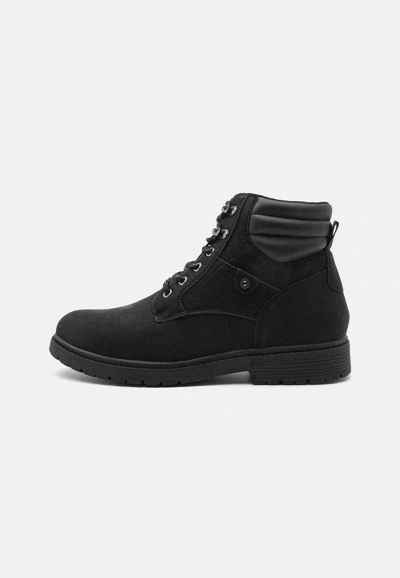 Bottine noire avec lacets à l'avant, col rembourré, détail bouton latéral et semelle en caoutchouc texturée sur fond blanc.