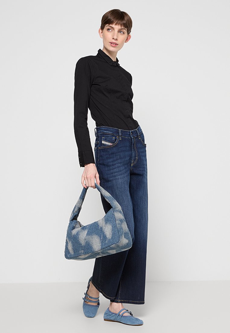 Jeans a palazzo in denim blu, camicia nera con colletto e bottoni, borsa leggera azzurro testurizzata con motivo, e scarpe flatte blu abbinate.