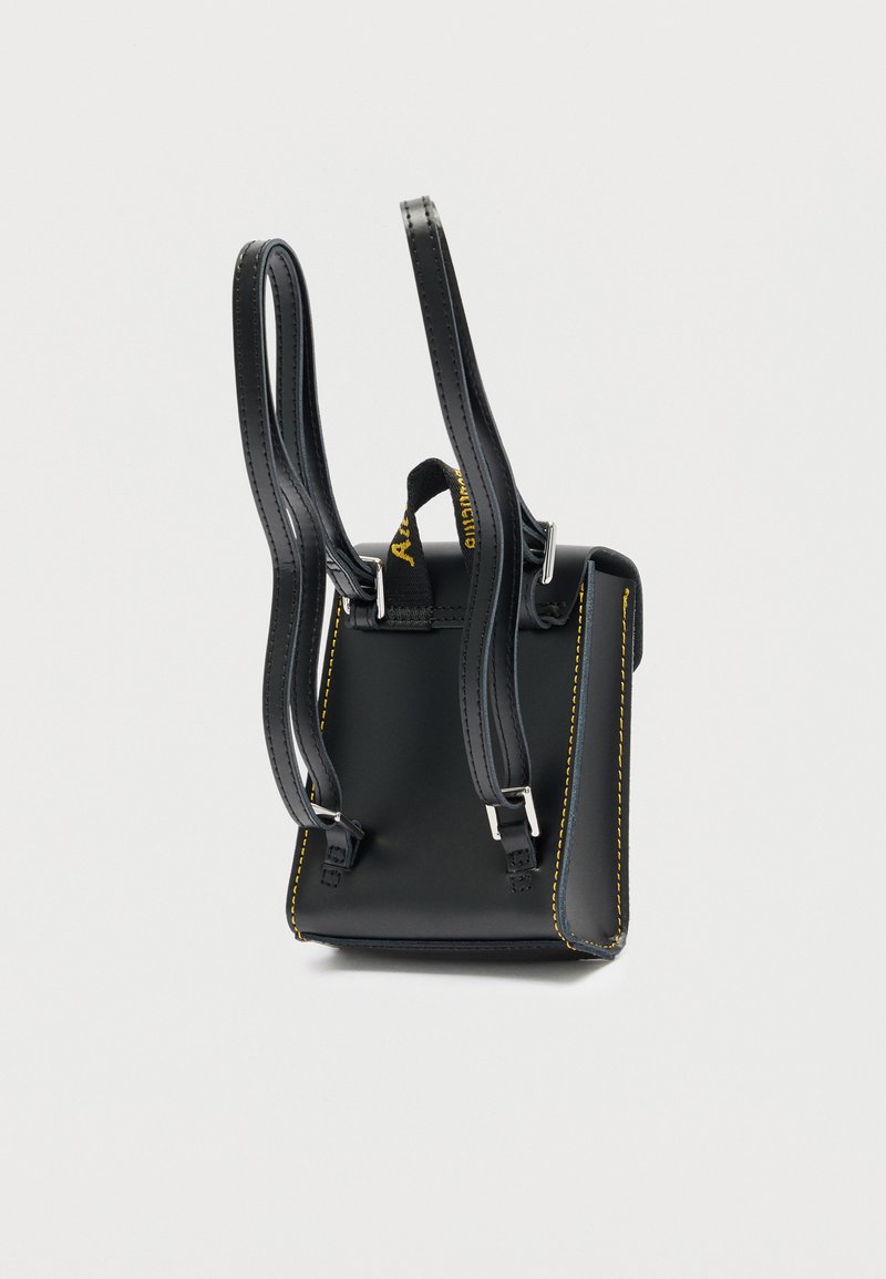 Piccolo zaino nero in pelle con cuciture gialle, spallacci regolabili e manico ad anello in tessuto nero.