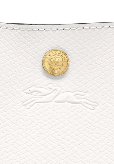 White textured leather bag featuring embossed greyhound logo and a gold-toned hardware button with brand name and year.