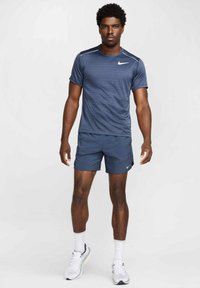 Camiseta atlética de color azul marino con textura a rayas, combinada con pantalones cortos a juego. Presenta el logo de Nike en blanco, cuello redondo y mangas cortas.
