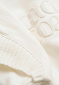 Witte sweatshirt met ribbels aan de mouwen en een gestructureerd, reliëfdesign. Zachte stof met een subtiele glans en een gladde afwerking.