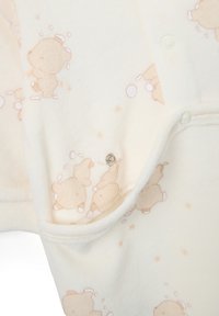 Crème fleece stof met een cartoon beer patroon in lichtbruin en zachte accenten. Voorzien van een metalen drukknoopsluiting en een gestructureerde afwerking.